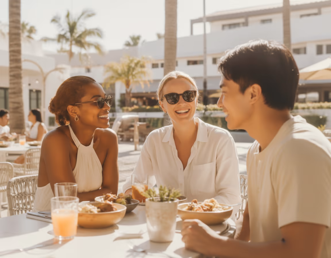 Friends laughing together over lunch on a sunny terrace